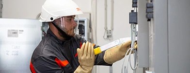 Electrician verificand siguranta unui tablou electric folosind echipament de protectie