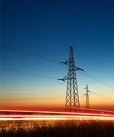 Stalpi de inalta tensiune la apus, simbol al infrastructurii moderne de transport al energiei pe reteleelectrice.ro