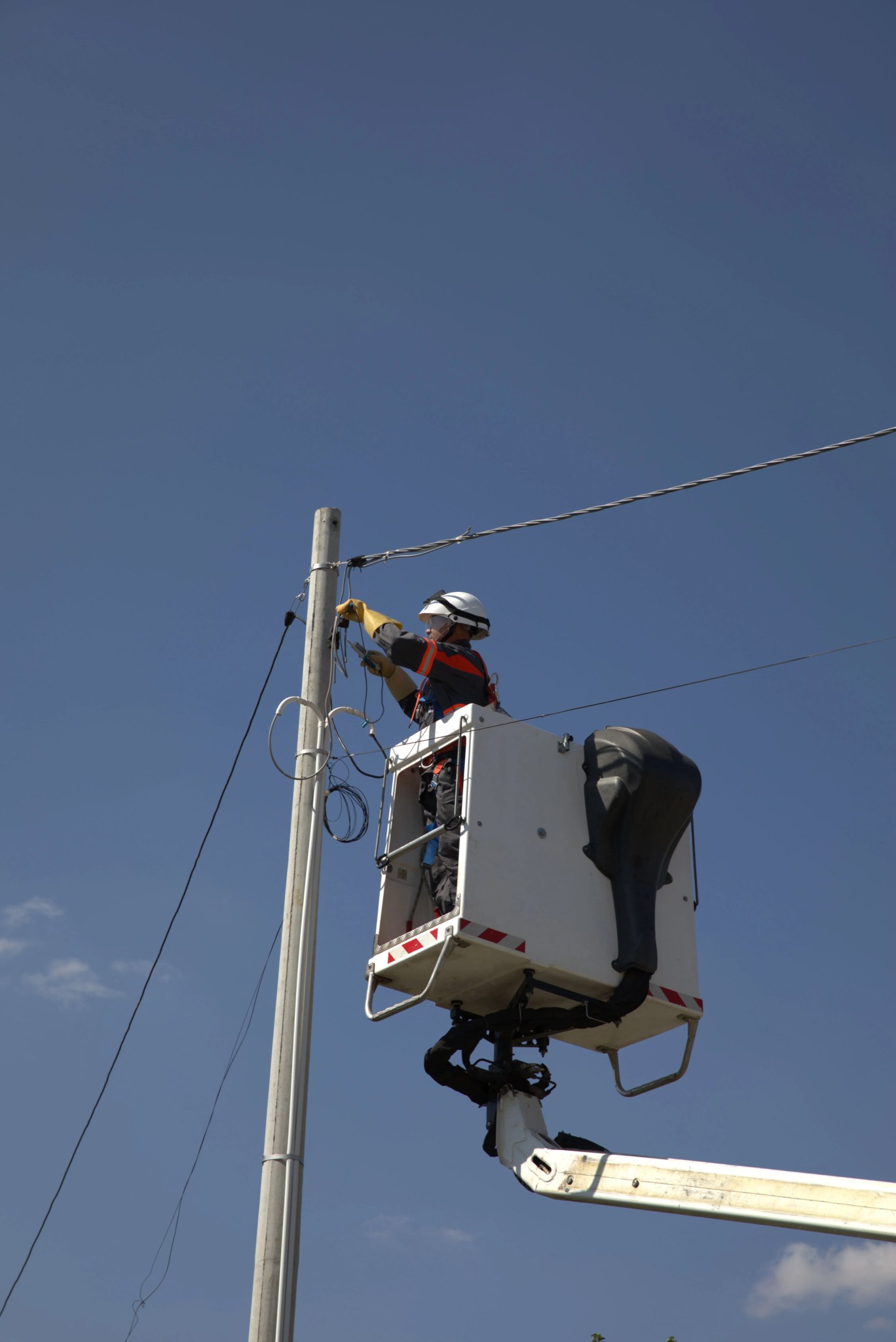 Electrician ridicat într-o nacelă pentru instalarea sau repararea liniilor electrice.
