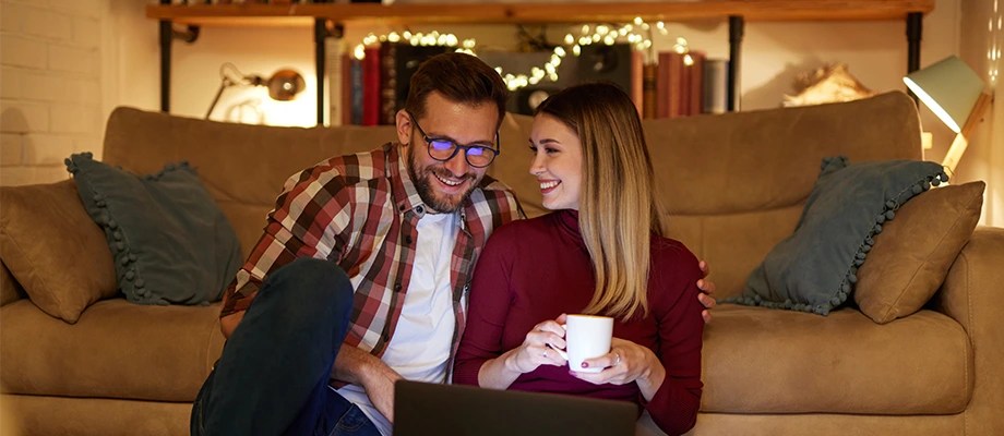 Cuplu relaxat acasa, bucurandu-se de confortul iluminatului eficient si accesibil